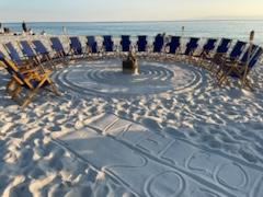 beach chairs on a sandy beach in a circle around a bonfire pit