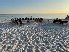 beach chairs on a sandy beach in a circle around a bonfire pit