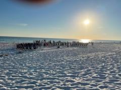 beach chairs on a sandy beach in a circle around a bonfire pit with the sun shining above