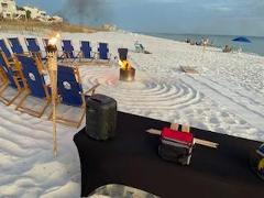 beach chairs on a sandy beach in a circle around a bonfire