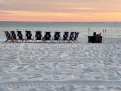 beach chairs on a sandy beach in a circle around a bonfire