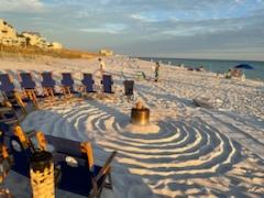 beach chairs on a sandy beach in a circle around a bonfire