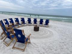 beach chairs on a sandy beach in a circle around a bonfire pit