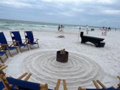 beach chairs on a sandy beach in a circle around a bonfire pit