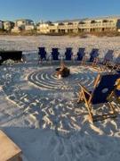 beach chairs on a sandy beach in a circle around a bonfire pit