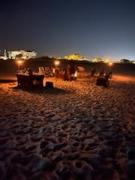 beach chairs on a sandy beach in a circle around a bonfire pt just as the sun is setting